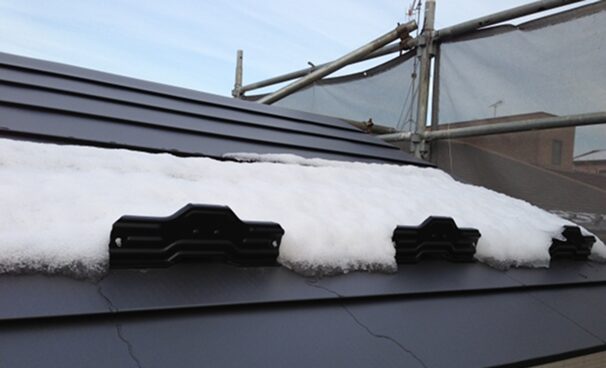 金属屋根に取り付けられた雪止め金具と積もった雪の様子