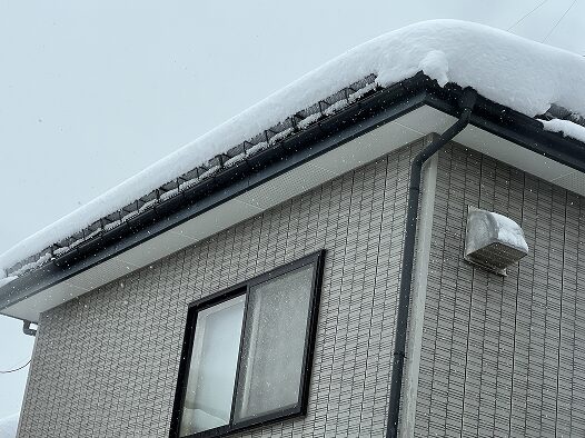 雪止め設置後の住宅屋根と積もった雪の様子